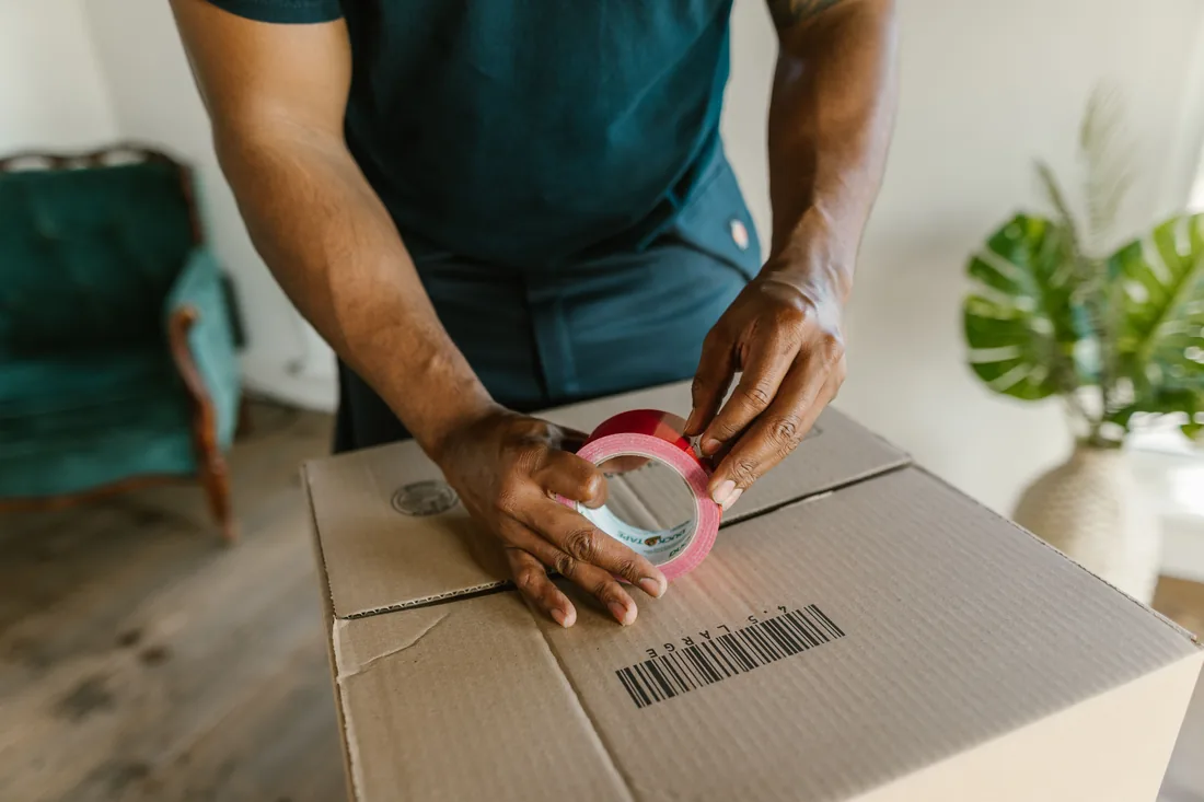 Persona sellando con cinta una caja de cartón lista para envío